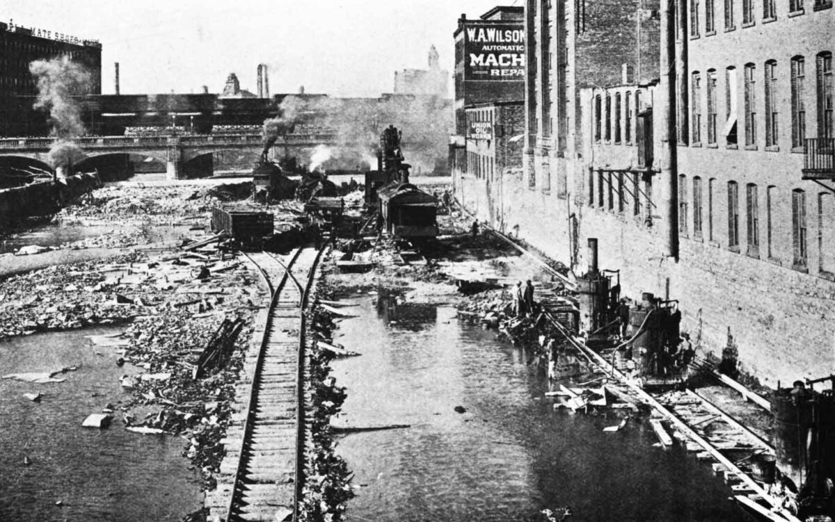 Steam shovels load broken stone into railroad cars in the bed of the Genesee River in October 1915. The view, probably from the Andrews Street Bridge, looks north toward the old Central Avenue Bridge. Channeling machines, lower right, cut slots to square off the cut and protect the building foundations. (Annual Reports of the Department of Engineering for the City of Rochester, 1914–1916, via Google Books.)